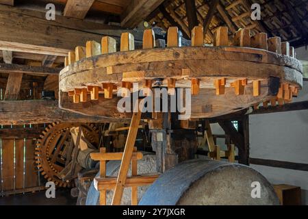 Millstones, cogwheels and wooden gear mechanism inside 18th century watermill / water wheel at open air museum Bokrijk, Limburg, Flanders, Belgium Stock Photo