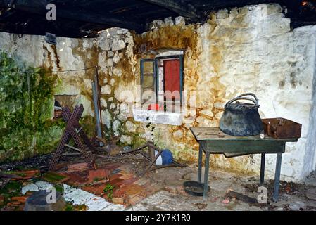 The interior of an abandoned building: moldy walls, blackened ceiling beams, things left by previous owners. Inside an old house in need of repair Stock Photo