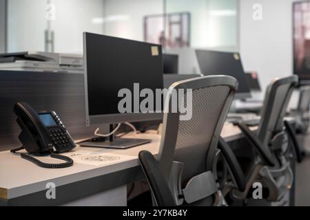 Modern office workspace featuring computer monitors, office chairs, and a desk phone. Stock Photo
