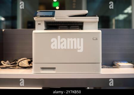 A modern office printer on a desk with blurred background. Stock Photo