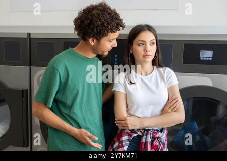 Young couple having a serious conversation in a laundromat during the day Stock Photo