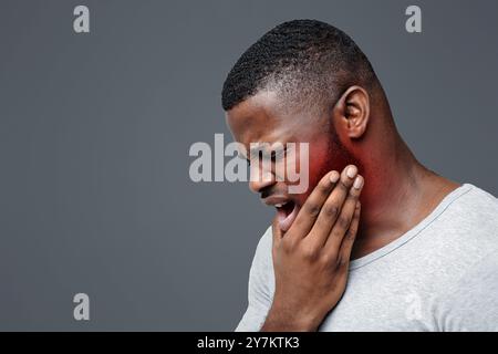 Young man having acute toothache, holding his jaw Stock Photo