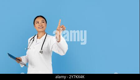 Doctor in a white coat explaining concepts on a blue backdrop Stock Photo
