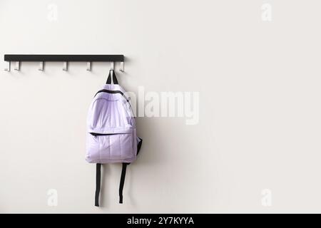 Stylish school backpack hanging on white wall in room Stock Photo