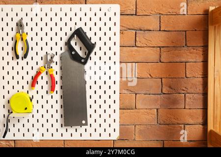 Pegboard with builder's tools on brick wall in workshop Stock Photo