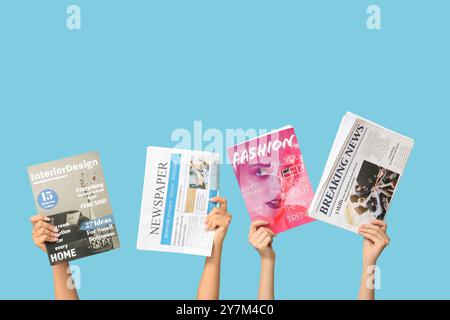 Female hands with different magazines and newspapers on blue background Stock Photo