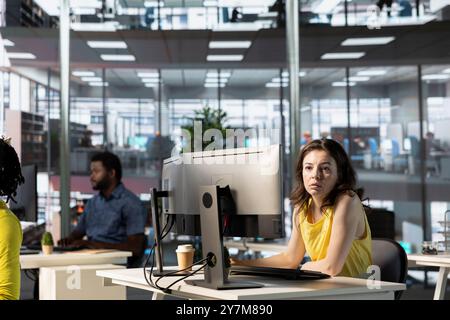 IT employees in office working at computer desks, testing and deploying programs and systems. Programmer and developers checking code on desktop PCs, solving tasks in workspace Stock Photo