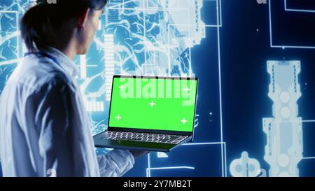 Precise admin using green screen laptop to write artificial intelligence script code in startup workplace. Skillful professional doing maintenance work in data center, updating AI systems Stock Photo
