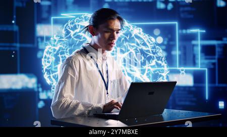 Efficient engineer in cloud computing company uses artificial intelligence computing simulating human brain. Focused admin running operations on laptop with AI machine learning algorithms Stock Photo