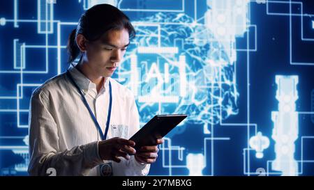 Asian developer using tablet to implement artificial intelligence parallel processing, breaking up complex computational tasks into smaller bits, enabling AI systems to process more input data faster Stock Photo