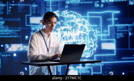 Engineer in technologically advanced workplace uses artificial intelligence computing simulating human brain. Admin in server hub running operations on laptop with AI machine learning algorithms Stock Photo