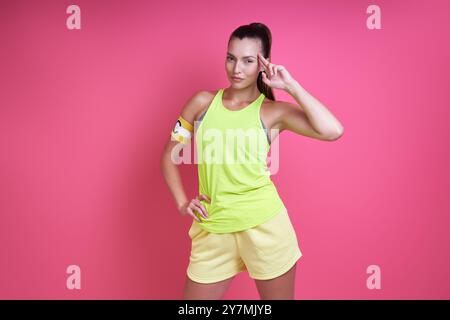 Confident woman in sports clothing wearing captain band and gesturing against pink background Stock Photo