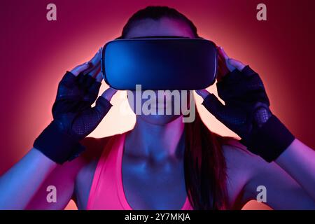 Young woman wearing virtual reality glasses against colorful background Stock Photo