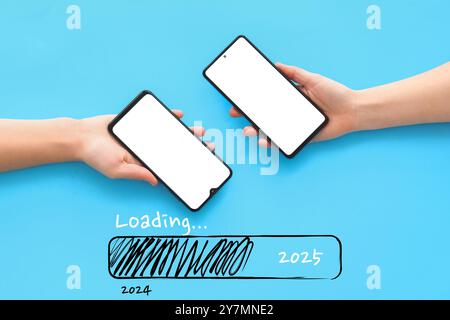 Hands holding mobile phones and status bar with year 2024 and 2025 on light blue background Stock Photo