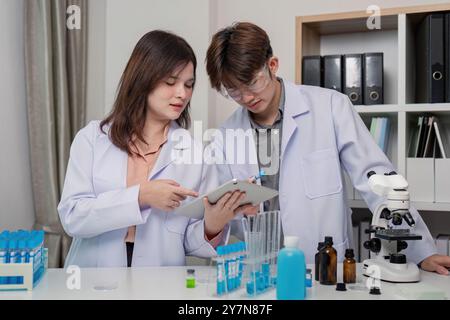Team of Laboratory Scientists Collaborating on Research Using Digital Devices Stock Photo