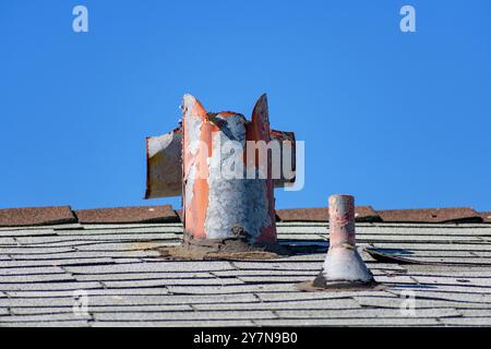 An old, rusted rooftop ventilation pipe with chipped paint, showing signs of decay and needing repair. Stock Photo