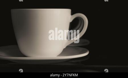 white ceramic cup on black background close up , black and white photo Stock Photo