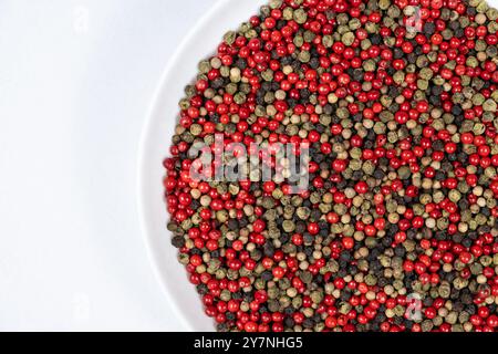 A mixture of different peppercorns on a white background, top view, copy space for text. Stock Photo