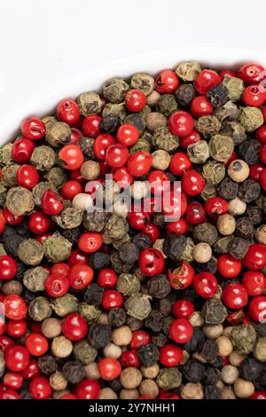 A mixture of different peppercorns on a white background. Stock Photo