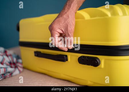 Vacation and travel concept. Elderly male hand to close bag the zipper after packing, preparing baggage case for journey, preparation for trip voyage. Stock Photo