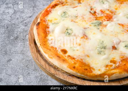 Four cheese neapolitan pizza on wooden cutting board on stone table Stock Photo