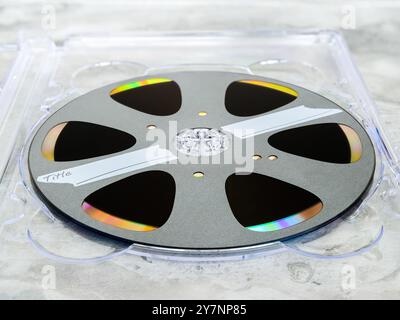 Recordable laser disc with a label stylized as an analog tape or film on a reel (bobbin) with an empty area for the title in a case Stock Photo