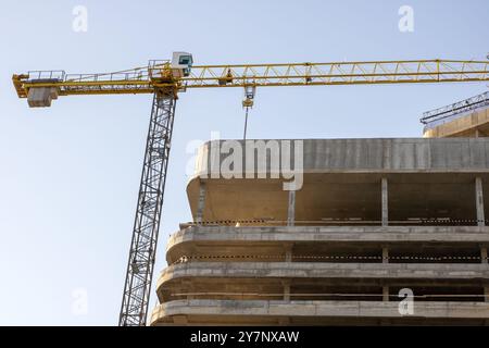 A bustling construction site featuring several cranes in action, and a significant building currently under construction, showing great progress Stock Photo