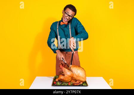Photo of classy young man speak phone cutting roasted thanksgiving turkey isolated on yellow color background Stock Photo