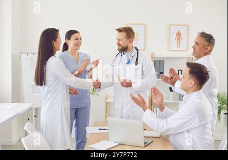 Happy smiling doctors shaking hands rejoicing at success in treatment standing in clinic Stock Photo