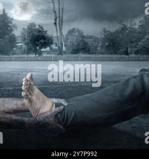 A zombie hand with a bloody wound grabs a human leg with full moon background. Scene has dark and scary. Zombie, devil, evil, satan, or monster hands. Stock Photo