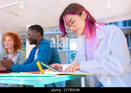 Three happy multiracial students studying with smartphones outdoors. Stock Photo