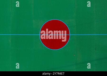 A bright red circle is painted on a green surface with blue lines marking the boundaries. Stock Photo