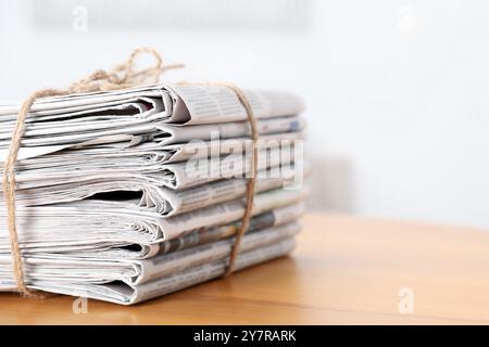 Stack of many newspapers on wooden table, space for text Stock Photo