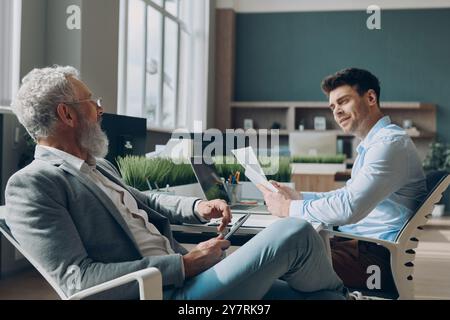 Two confident businessmen communicating while working in the office together Stock Photo