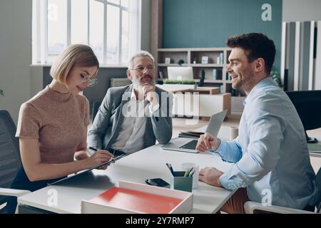 Happy young man having interview with HR managers while sitting at the office desk Stock Photo