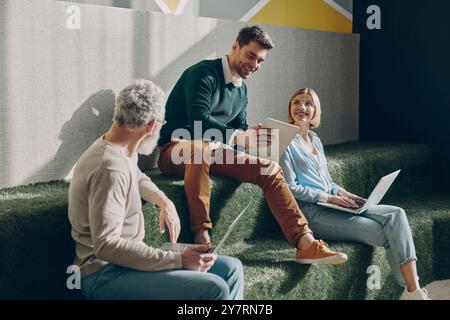 Confident business people talking and using technologies while working in creative office Stock Photo
