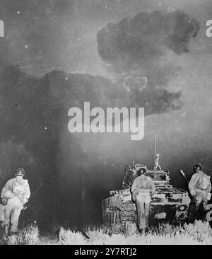 CLOSING IN ON " GROUND ZERO "Yucca Flat, Nevada ..... Sixth Army troops from Camp Desert Rock are moving behind one of the tanks that led them towards " Ground Zero " after the latest Atomic explosion at Yucca Flat on 1 June. The atomic cloud looks like a sinister fist poised over tank and men in the murkiness of the dawn. The troops were in foxholes 7000 yards from the blast when it was touched off. They advanced towards Ground Zero until halted by radiological safety rules. 4 June 1952 Stock Photo