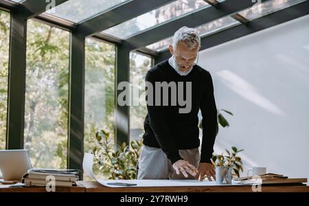 Confident mature architect examining blueprint while working in the creative office Stock Photo