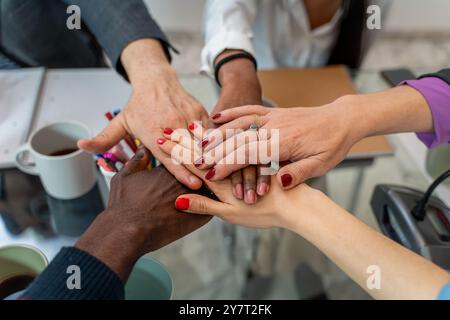 Close-up of diverse business team joining hands over office desk. Symbolizes unity, teamwork, and workplace diversity. Concept of collaboration, inclu Stock Photo
