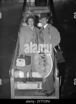 PIDDINGTONS ARE BACK - WITH SOUVENIRS OF ZUZULAND    Mr Sydney Piddington and his wife Lesley - Australian mind-reading partners who made a hit on British radio - pictured on arrival at London airport by South African Airways liner this evening. Mr Piddington is carrying Zulu shields, presented to him in Zululand, as a souvenir of their nine weeks tour of South Africa. The Pittington's are to have a holiday in London before leaving on December 17 for a sixteen weeks tour of Australia.    29 November 1950 Stock Photo