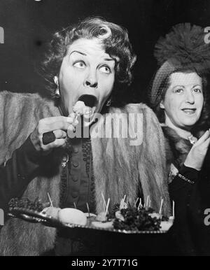 BITING COMMENT   Biting comment on the menu the size of the kick-bits usually served at cocktail party's is passed by film star Martha Raye , shown here as she attacks the canape with open-mouthed enthusiasm during a holiday cocktail party in Hollywood.  30 December 1950 Stock Photo