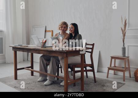Two confident businesswomen using technologies while working together at the creative office Stock Photo
