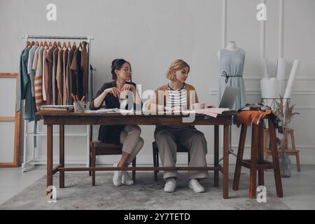 Two female fashion designers working on new collection in workshop together Stock Photo