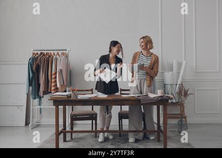 Two happy female fashion designers working in workshop together Stock Photo