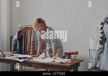 Young female fashion designer looking concentrated while working on new collection Stock Photo