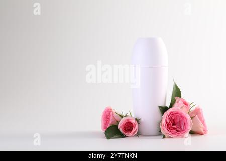 Roll-on deodorant and beautiful rose flowers on white background, space for text Stock Photo