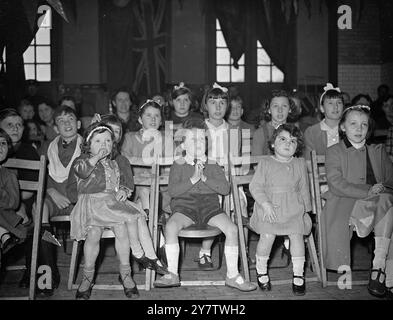 FIREMEN GIVE PARTY TO CELEBRATE BRITHDAY OF THEIR EIGHT YEAR OLD GIRL. To celebrate her eighth birthday firemen, and women at Woodside Fire Station gave a party to little Doreen Legg, whom they have adopted under the London fire Service Benevolent Scheme.  Doreen's father was killed in a big london raid while on duty with the NFS. The adopted child's new uncles and aunties hope to provide Doreen with an annuity until she is 14.  Photo shows: A study in expressions as the children watched the conjurer at a party in honour of the birthday of Doreen Legg 'adopted' girl of the firemen of Woodside Stock Photo