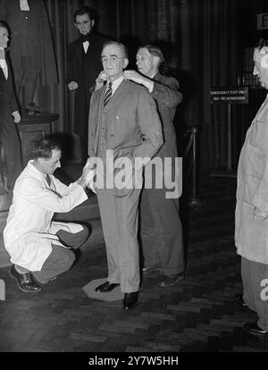 PRESIDENT TRUMAN ' S IMAGE WEARS HIS OLD SUIT: BUT THE HEAD OF AMERICA IS MISSING President Truman heard that the wax model of himself, made for Madame Tussauds collection in London, was in need of appropriate clothing.  Accordingly he selected one of his older suits in a grey plaid design and a shirt and tie, and gave his outfit to Mr T L Rowan, Mr Attlee's secretary, to bring to London when he left Washington along with the Prime Minister. Photo Shows: Mr Bernard A Tussaud dressing the wax image of Mr Truman in the President ' s suit of clothes, while Abraham Lincoln betrays somewhat startle Stock Photo