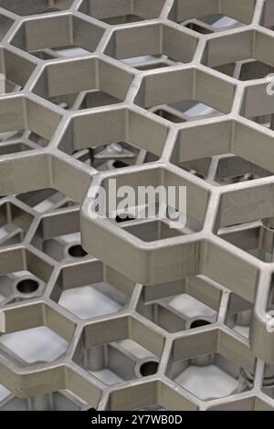 Openwork three-dimensional metal grid with hexagonal cells. Close up shot, abstract metalwork industry background. Stock Photo