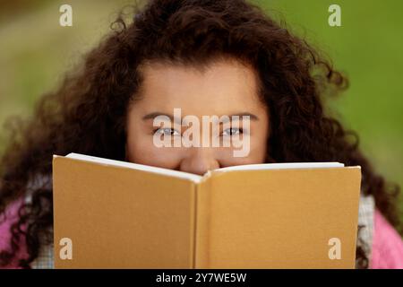 Young lady enjoying reading a book outdoors in bright sunlight Stock Photo